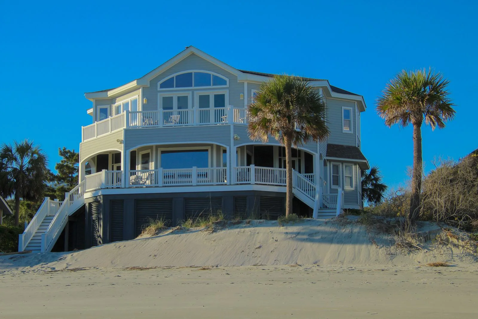 Real elevated coastal home with palms and a broad covered porch